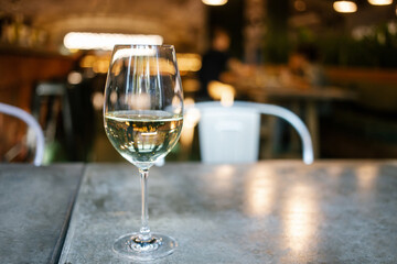 Glass of white wine in restaurant setting.