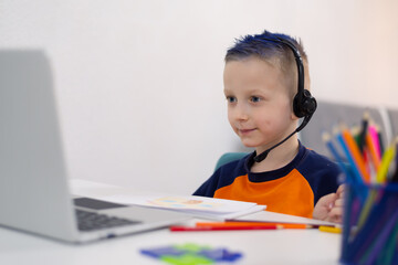 Naklejka premium Distance learning and online education. Schoolboy boy studies at home and does school homework. Remote learning during corona pandemic