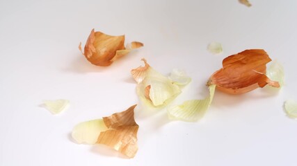 Peels of yellow onion falling down the table during cooking, peeling onion for making homemede food