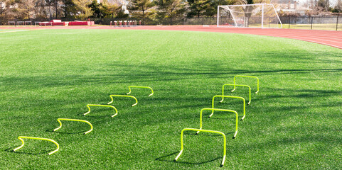 Yellow mini hurdles on turf field for speed and agility practice