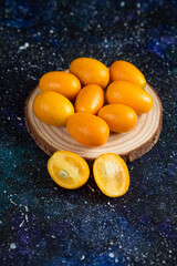 Fototapeta na wymiar Vertical photo of kumquats over wooden board
