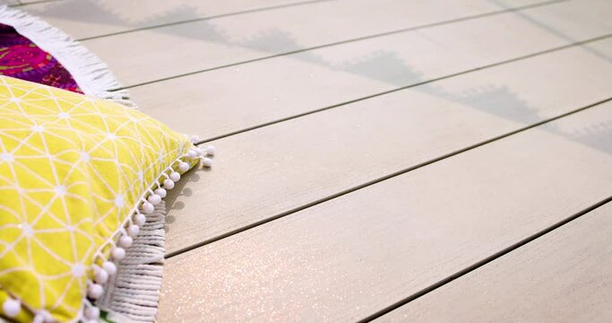 colorful pillows and rugs on sparkling decking at sunny summer day