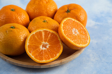 Close up photo of fresh mandarins on wooden plate