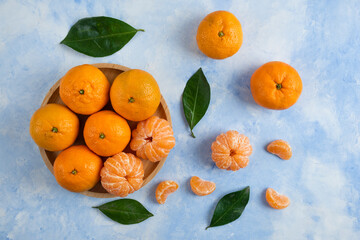 Top view of organic clementine mandarins peeled or whole over blue background