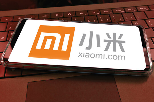 Close-up of smartphone screen with logo lettering of chinese xiaomi mobile phone company with computer keyboard background