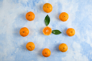 Pile of clementine mandarins and leaves on blue background