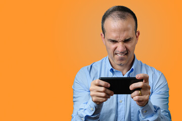 Mature man in formal wear playing on his smartphone and biting his lower lip.