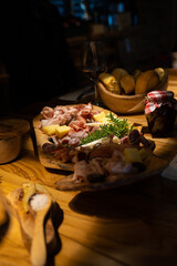 Wine with sausage appetizers on wooden plate.
