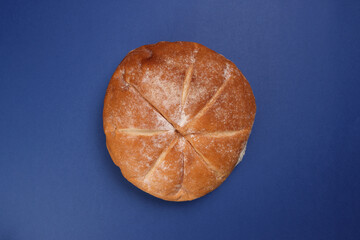 Freshly baked bread loaf round on blue background