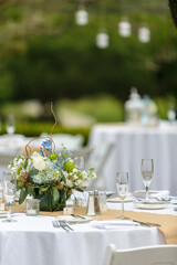 Tables set for an outdoor wedding reception in white, with blue flowers as decor