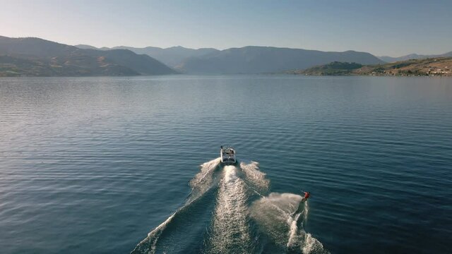 Drone Following Boat Towing Wakeboarder on Scenic Lake Chelan with Desert Mountains