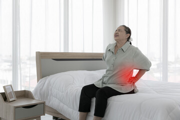 Senior woman feels back pain. sad senior older lady suffers from low-back lumbar pain sitting on...