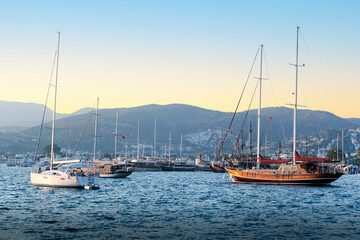 Fototapeta premium Luxury yachts docked in marina at sunset. Beautiful yachts at coast Aegean sea in Bodrum, Turkey.
