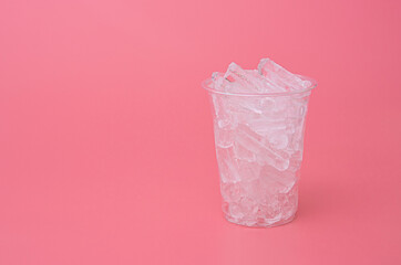 Ice in the plastic cup on pink background