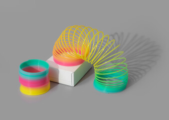 Rainbow plastic spring toy with shadows on gray background