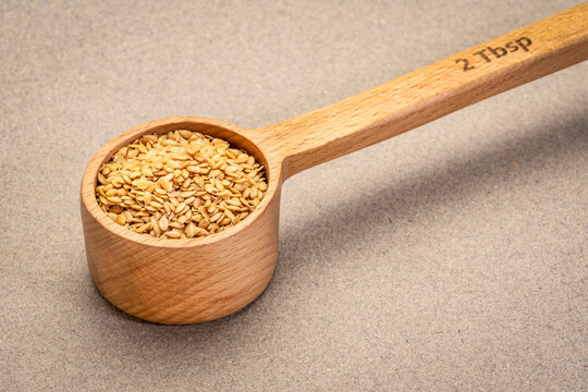golden flax seeds in a wooden scoop (2 tablespoons), superfood supplement and ingredient