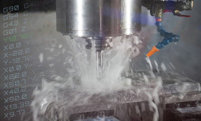 CNC milling machine cutting workpiece with coolant. CNC programming code. Industrial manufacturing...