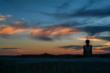 Woman silhouetted against a beautiful sunset on mountain top in the Badlands