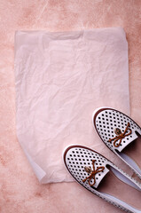 Light women's shoes with a bow and perforation on a brown background.