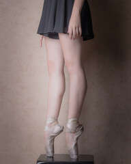 Legs of Caucasian white woman dancer artist standing on tiptoe with ballet slippers on a black cube © ALEJANDRO