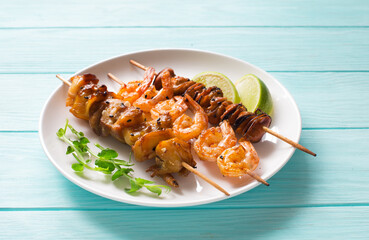 Mussels, shrimps and clam skewers on white plate  close up