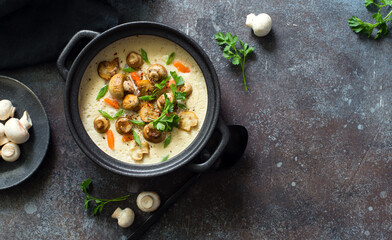 Bowl of hot  cheese and mushrooms cream-soup on gray stone background close up
