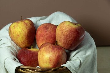 Apple fruits in wooden basket on neutral background.