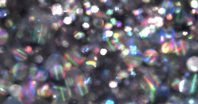 Soft and blurry bokeh glitter background with shiny floating particles with a shimmering rainbow reflection.