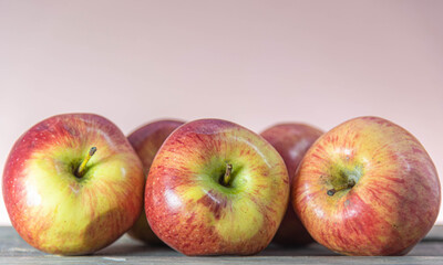 Red apple fruits on wooden surface on neutral background.