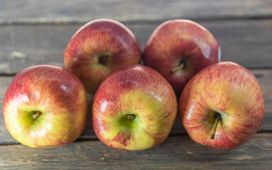 Red apple fruits on wooden surface on neutral background.