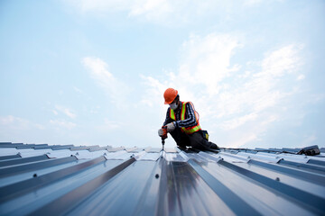 Builders in work clothes install new roofing tools, roofing tools, electric drill and use them on new wooden roofs with metal sheets © somchai20162516