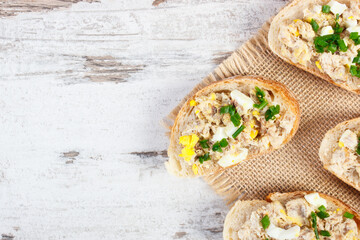 Baguette with mackerel or tuna fish paste, copy space for text on rustic plank