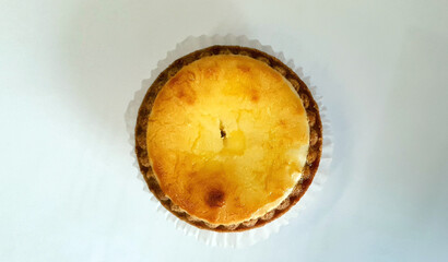 Top view of the circle shape baked cheese tart on paper on white background
