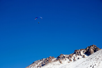 paraglider flying over the mountains on a sunny day