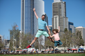 Excited father and son jumping on urban city background. Concept of friendly family.