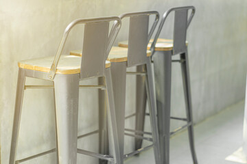 Bar stool in the loft style shop near the window glass with morning sunshine from outside. Window bar stools in cafes 