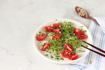 Heathy eating food. Organic tomato salad with micro basil greens on gray background with copy space
