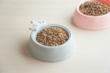 Dry dog food in bowl on wooden table