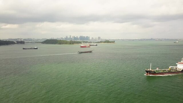 Sped up drone shot of ships sailing Singapore straits with city background