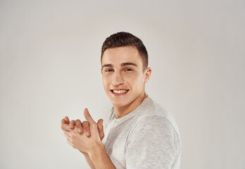 cheerful man gesturing with his hands in a white t-shirt light background cropped view