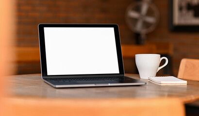 Fototapeta premium Mockup blank screen laptop with coffee and notebook on the table, Taken from the front.