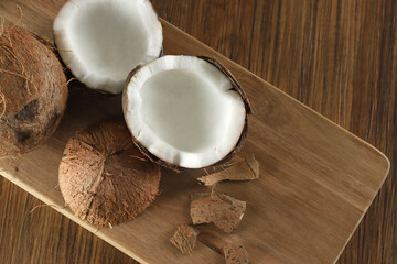 Fototapeta na wymiar Half ripe coconut cut on a wooden background. Ripe coconut cut in half on a wooden background