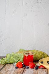 Strawberry jam and strawberry fruit placed on a wooden table
