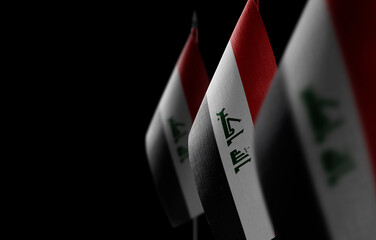 Small national flags of the Iraq on a black background