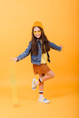 Beautiful young girl playing with a rainbow slinky, a toy of her childhood on studio background