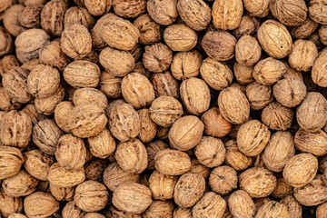 Walnut background with multiple walnuts on athe market laying in formation.