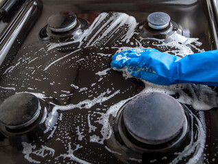 Woman with protective glove wipe down an oven range top