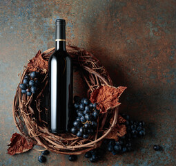 Fototapeta Bottle of red wine with grapes and dried vine leaves on an old rusty background. obraz