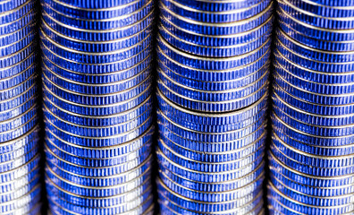many round metal coins of silver color illuminated in blue