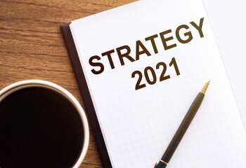 STRATEGY 2021 - text on notepad on wooden desk.